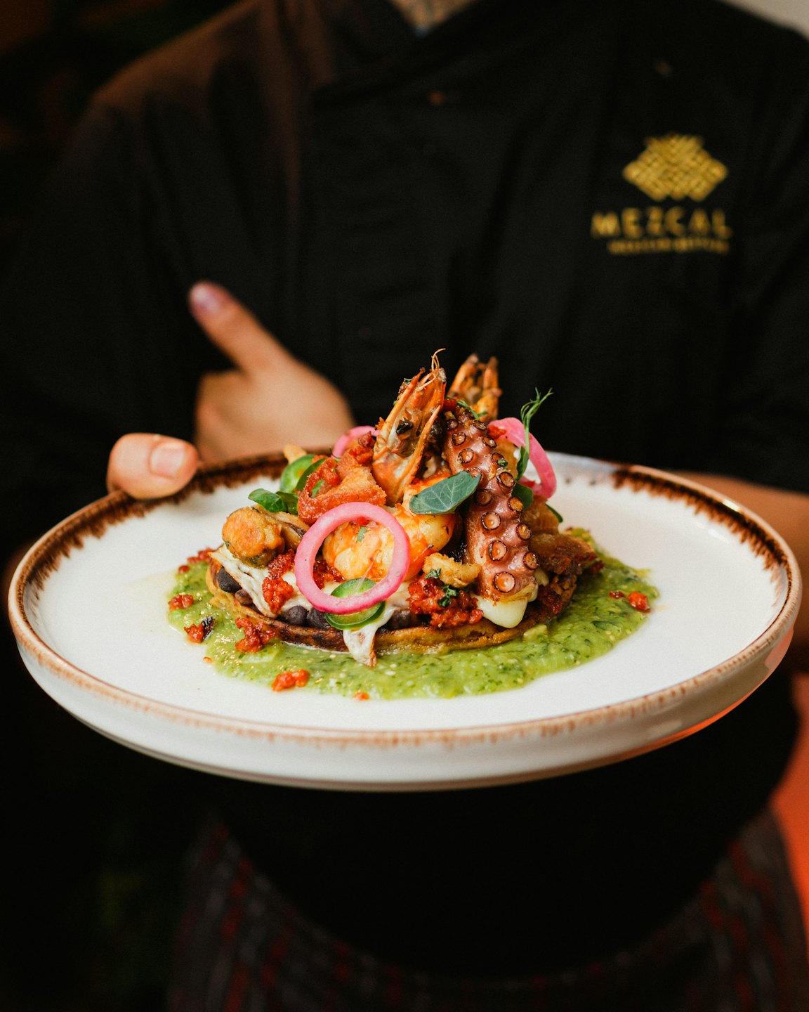Chef presenta un plato gourmet de mariscos con pulpo y camarones.