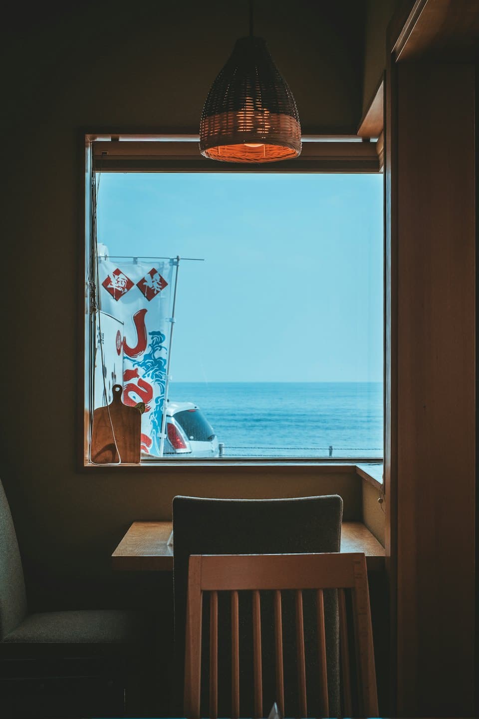 Interior de cafetería con mesa de madera con vistas al mar.