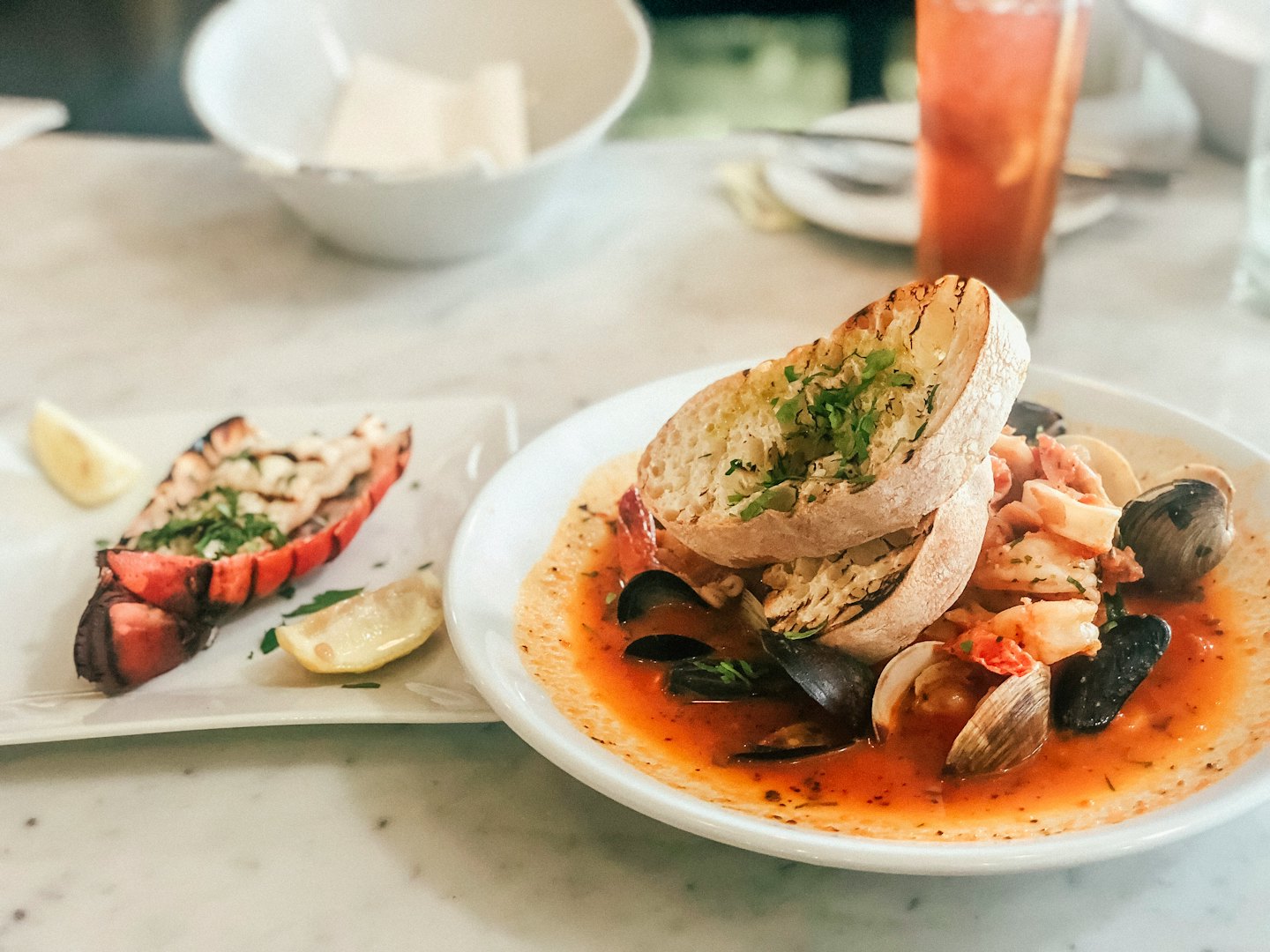 Mesa de restaurante con platos de langosta y guiso de mariscos.